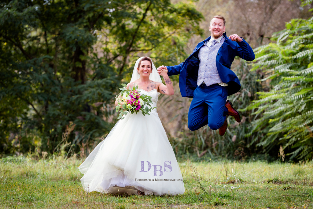 glücklicher Bräutigam springt in die Höhe neben seiner Braut